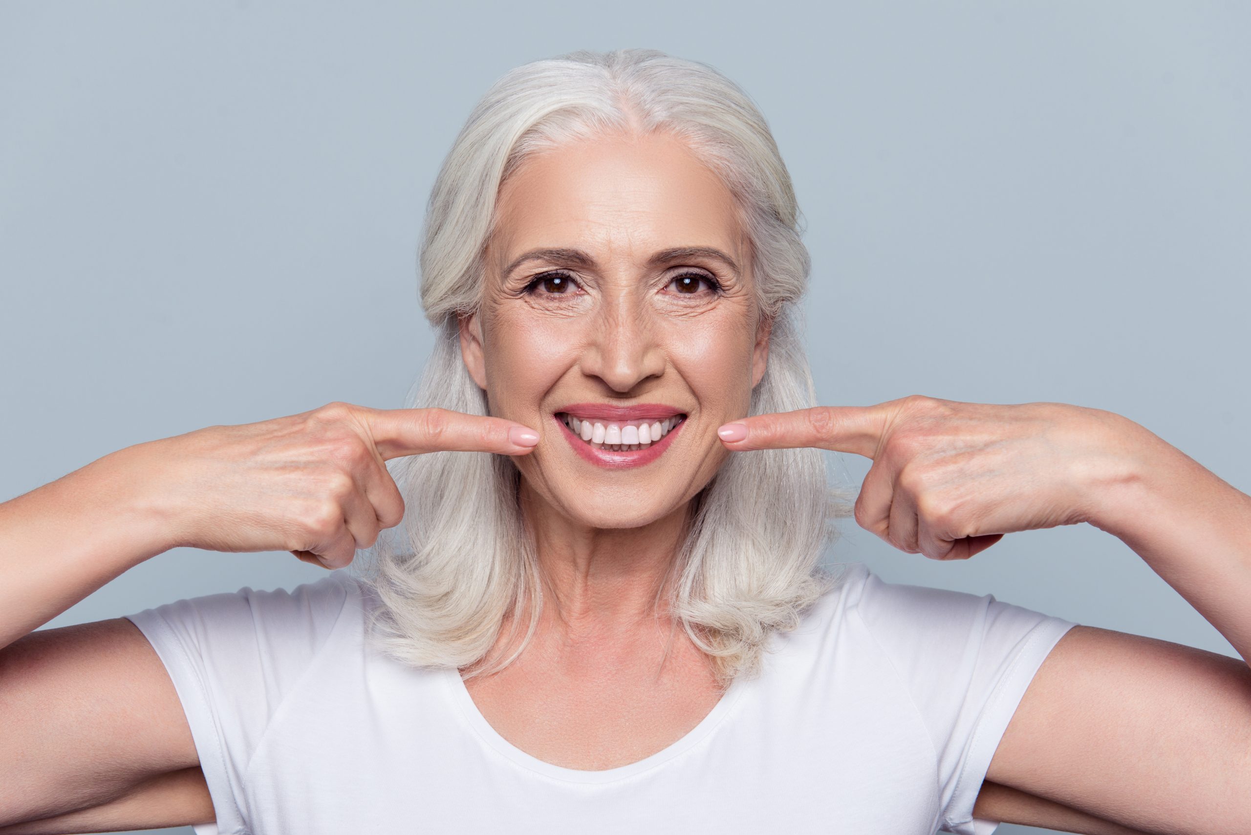 older woman pointing at her smile