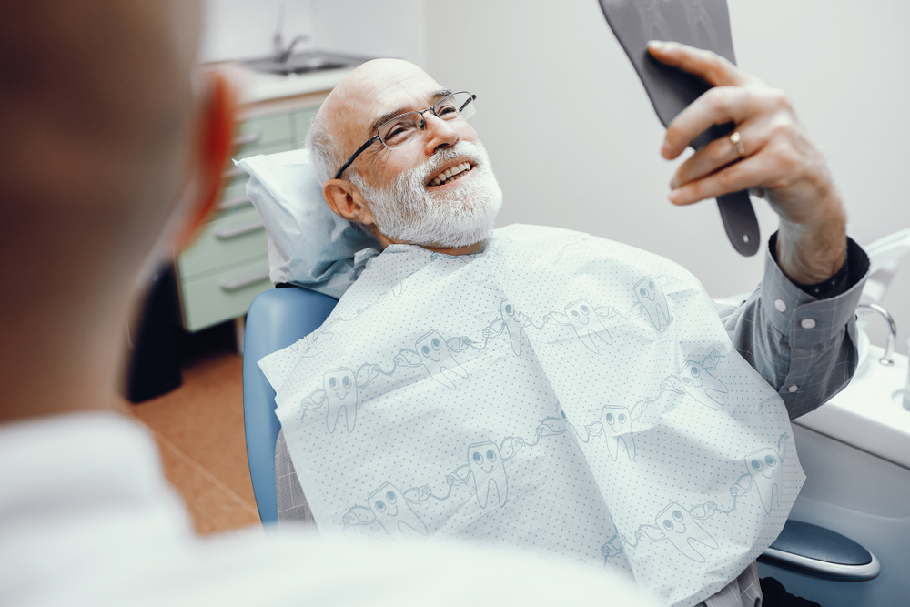 older man looking at his new smile at the dentist