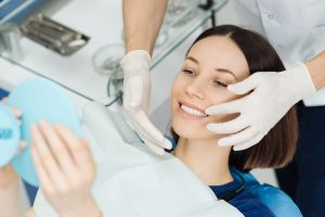 a woman smiles after her supplemental procedures that helped her become a better candidate for dental implants